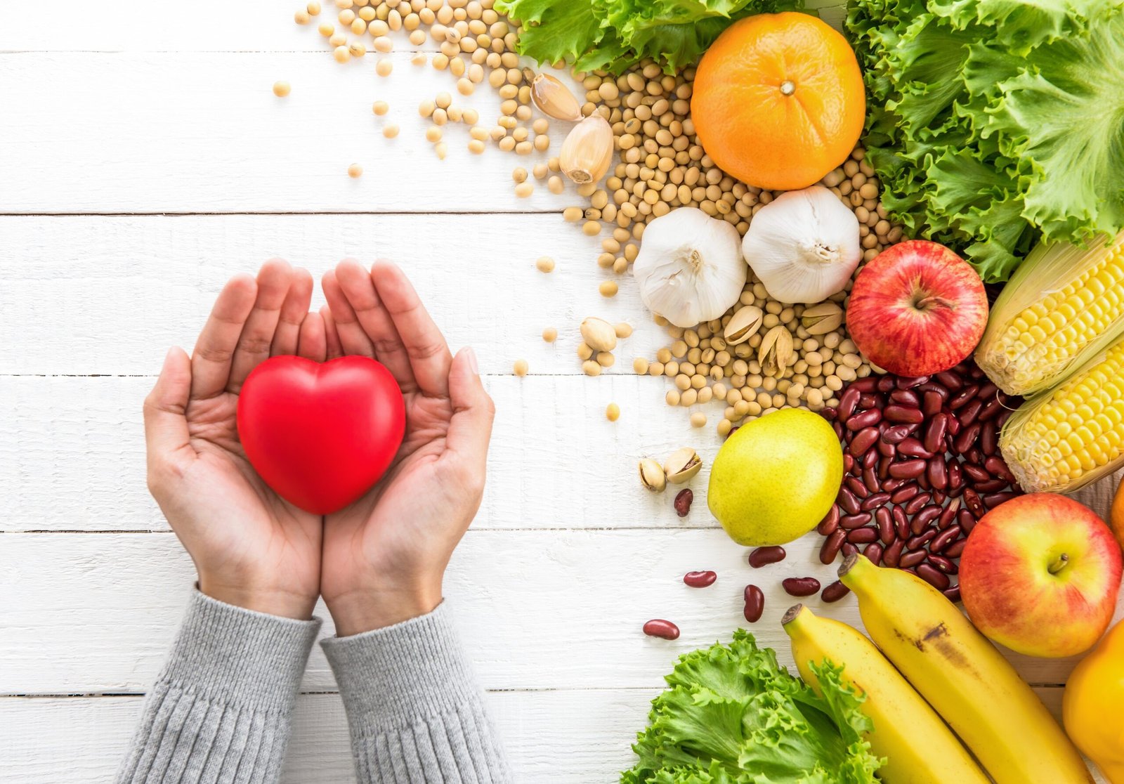 Woman hands showing red heart ball with healthy food aside