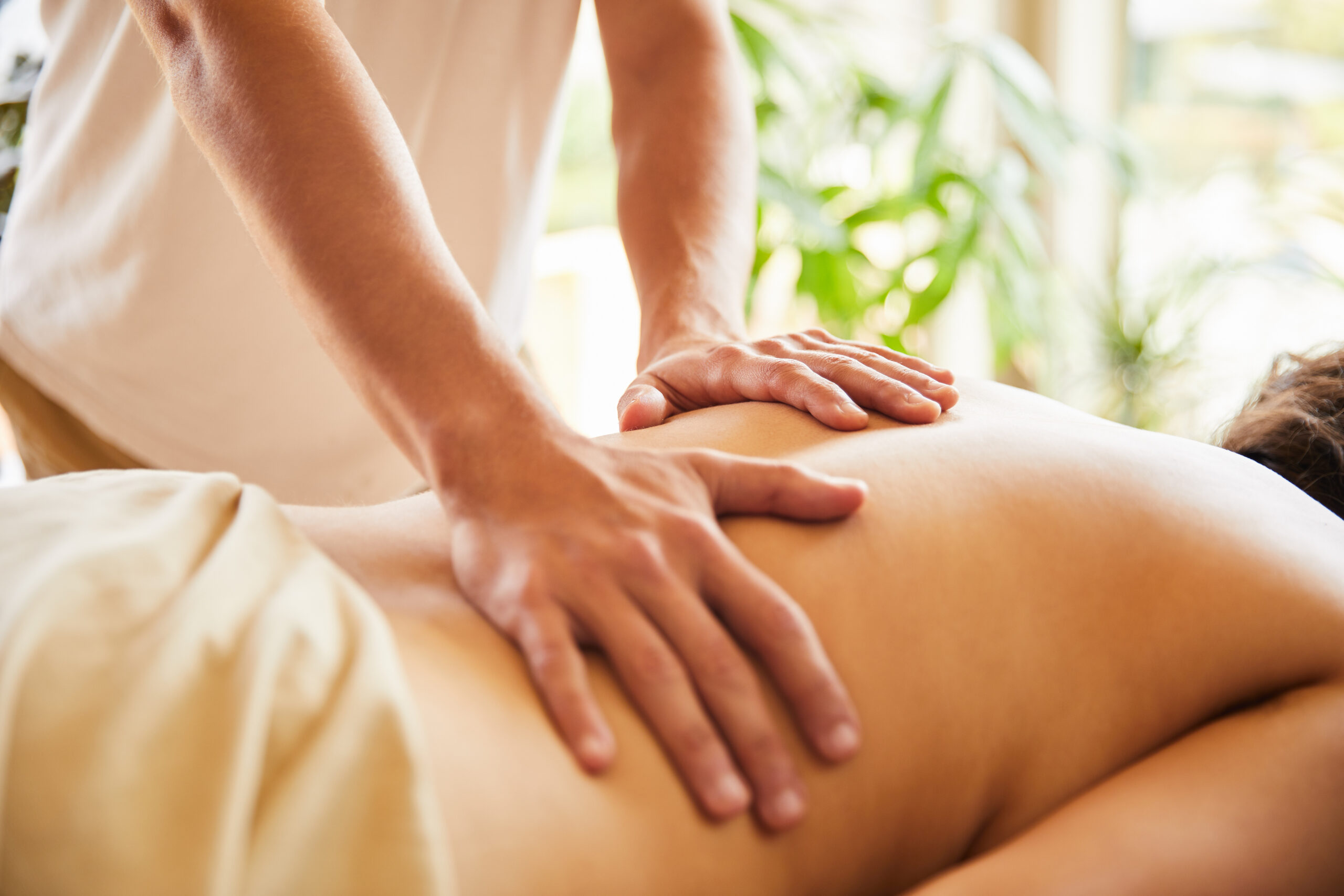 Male massage therapist work on a woman's back